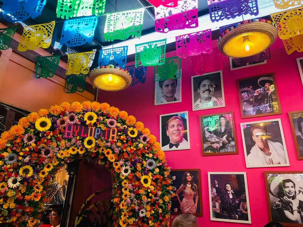 Salón de Ay Lupita con papel picado y arco de flores